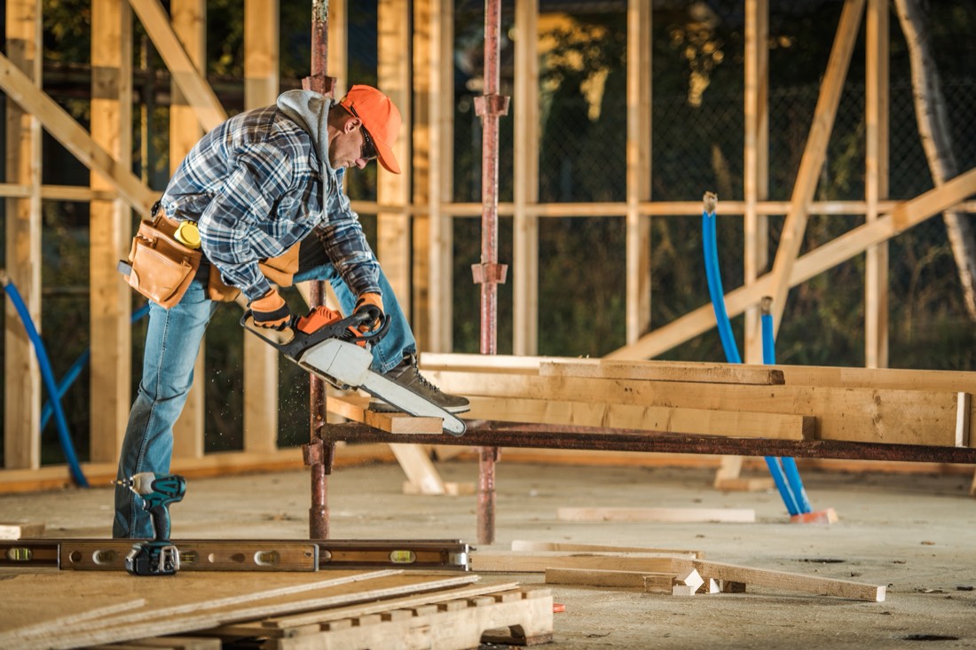 Handwerker beim Zuschnitt von Konstruktionsholz auf der Baustelle